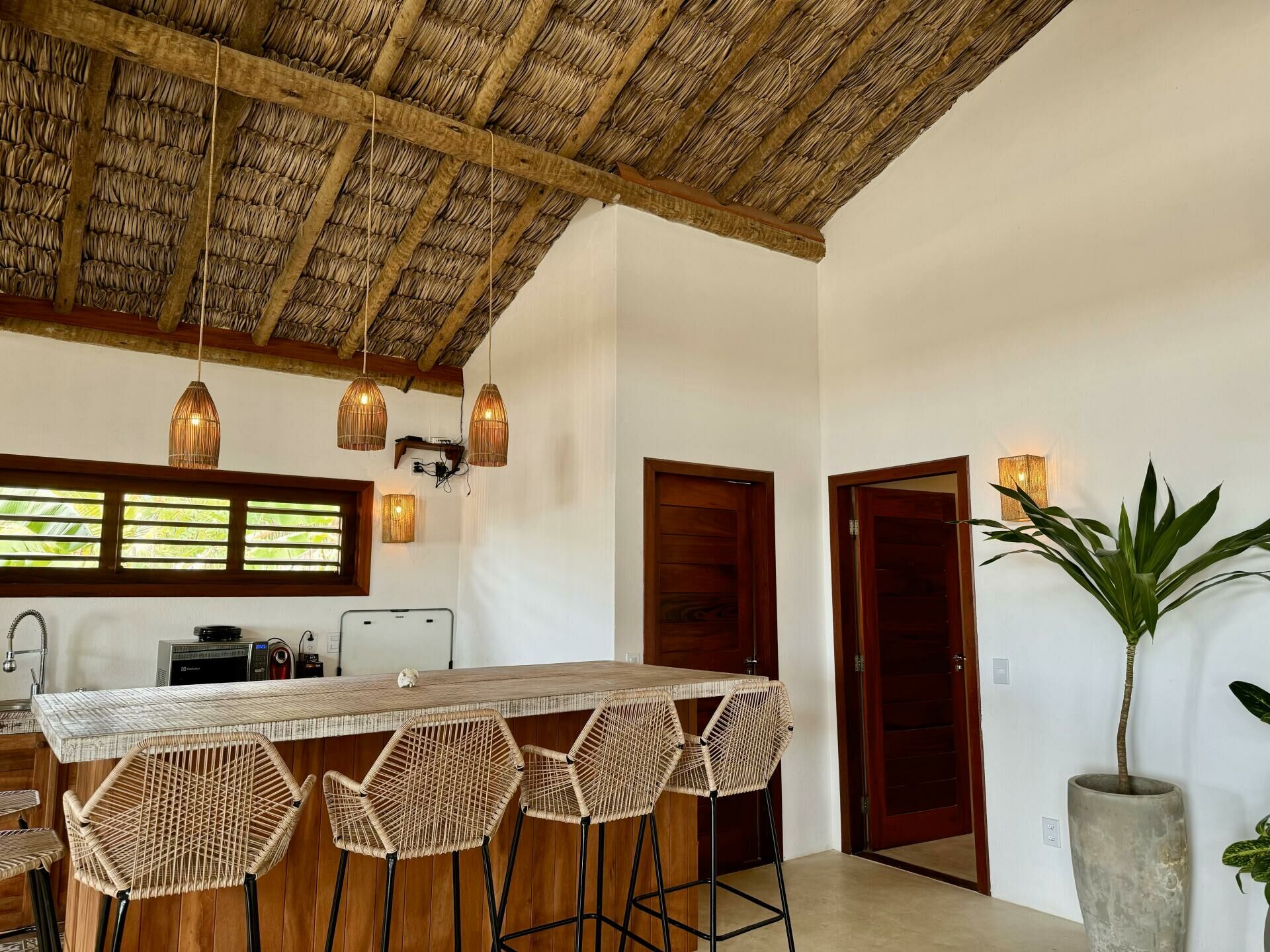 Imagem de Casa com vista para o mar e piscina, com arquitetura que apresenta detalhes em palha e madeira, em Icaraizinho de Amontada